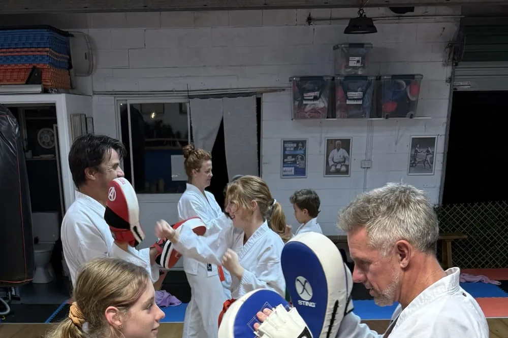 Teen girl in gi doing pad work with an instructor at Yushukan Karate